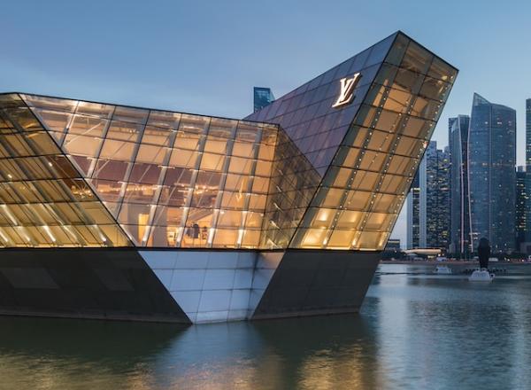 Illuminated polyhedral building Louis Vuitton over the water at Marina Bay in the evening, with skyscrapers of the Central Business District in the background, Singapore. License